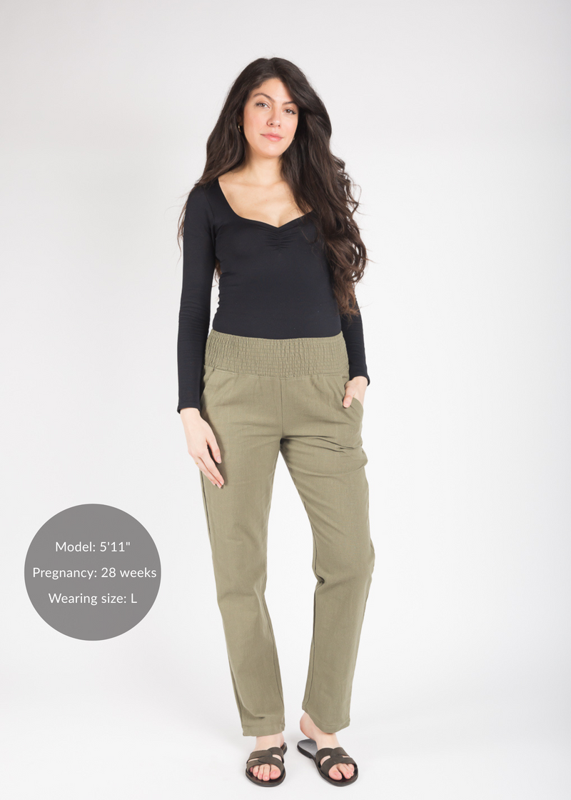 Tall pregnant woman in olive green linen smocked maternity pants with pockets.