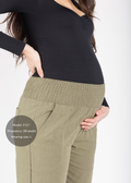 Taller pregnant woman in olive green linen smocked maternity pants with extended inseam.