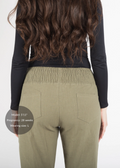 Back view of a pregnant model wearing olive green linen maternity pants with a smocked waistband.