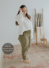 Woman in olive green linen smocked maternity pants with extended inseam, paired with a white shirt.