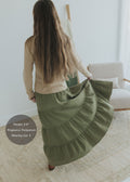 Woman in a long, flowing olive green tiered cotton-linen skirt with an elastic waistband.