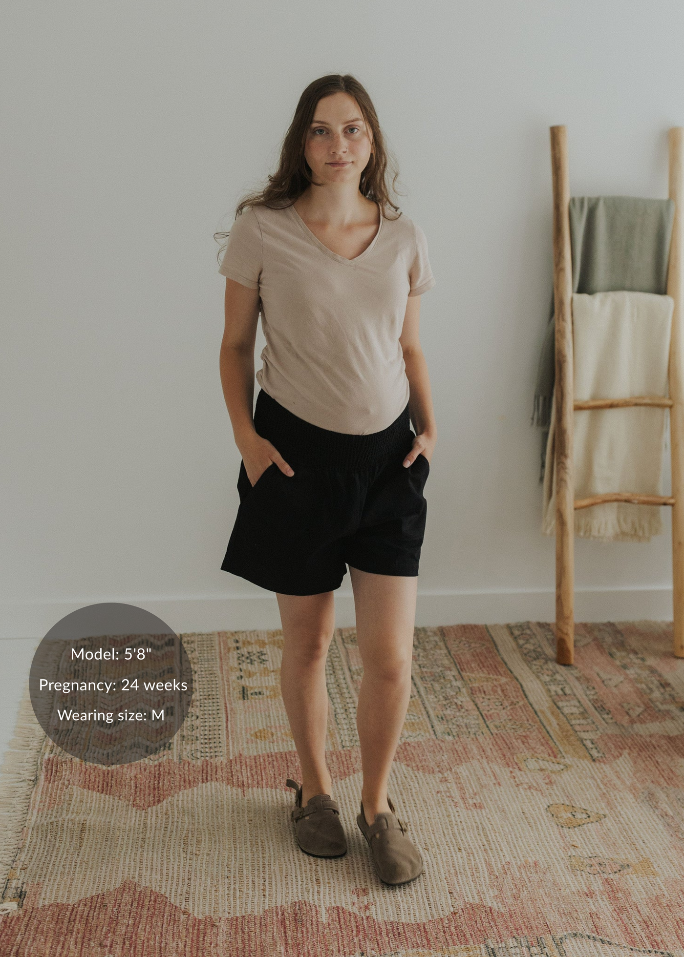 Woman in black smocked cotton/linen shorts with deep pockets and a beige t-shirt.