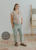 Pregnant woman wearing light green cotton gauze Everyday Breeze Pants with an elastic waistband and deep pockets.