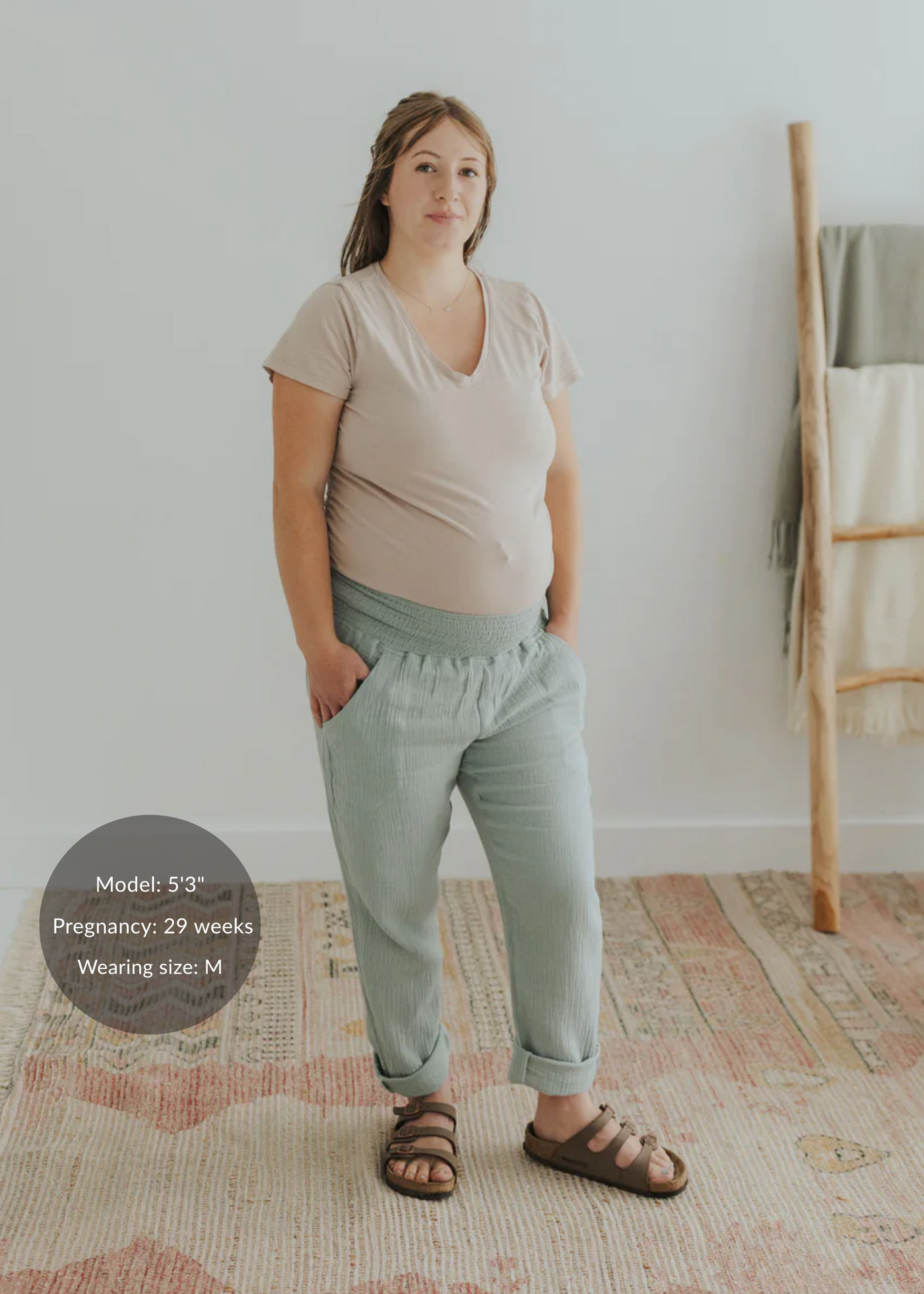 Pregnant woman wearing light green cotton gauze Everyday Breeze Pants with an elastic waistband and deep pockets.