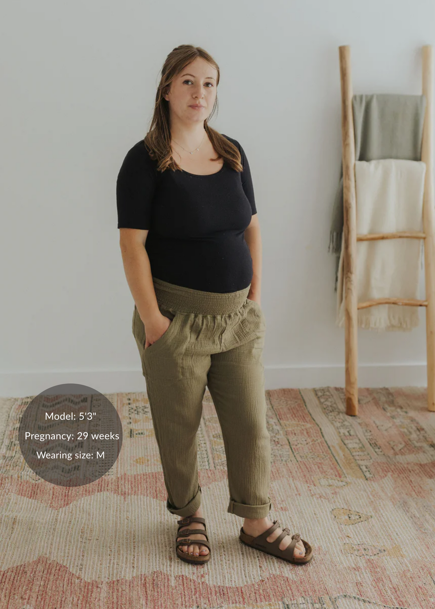 Pregnant woman in olive green cotton gauze Everyday Breeze Pant with elastic waistband and pockets.