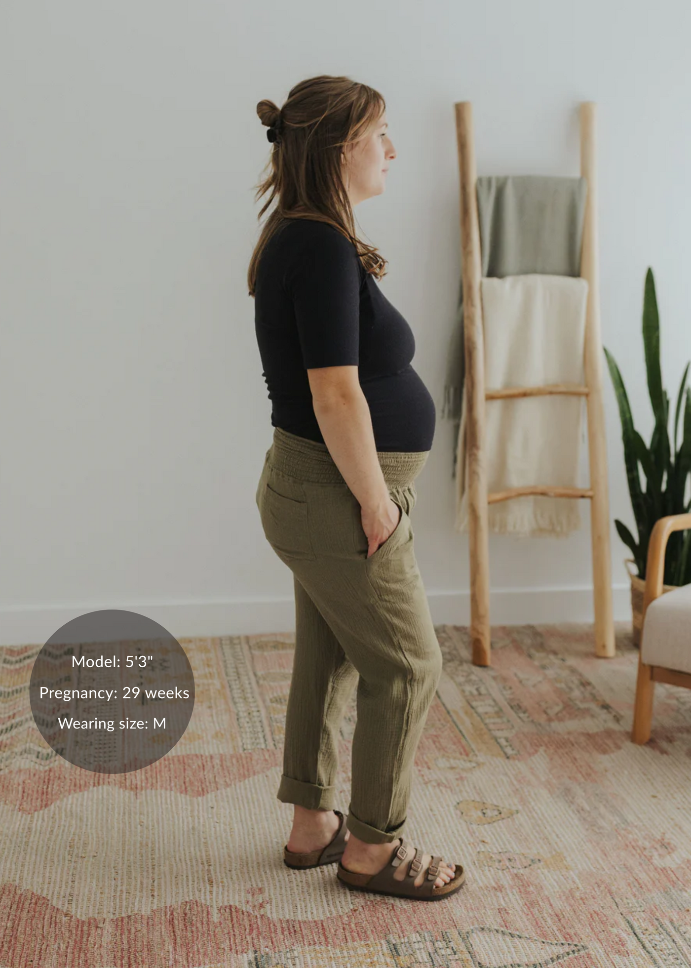 Pregnant woman in olive green cotton gauze Everyday Breeze Pant with elastic waistband and pockets.
