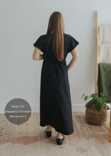 Back view of a model wearing a black cotton poplin waist-gathered maxi dress.