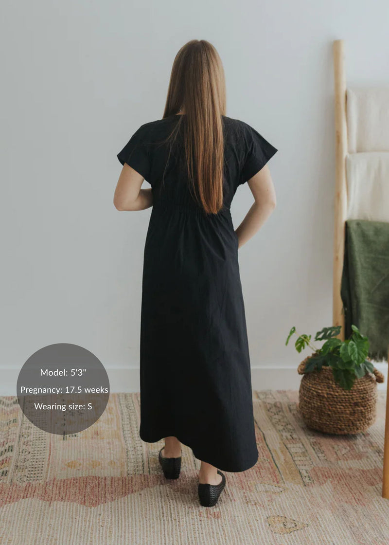 Back view of a model wearing a black cotton poplin waist-gathered maxi dress.