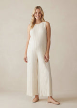 Smiling woman in a sleeveless white pleated Tencel jumpsuit with wide legs and a flowy fit.