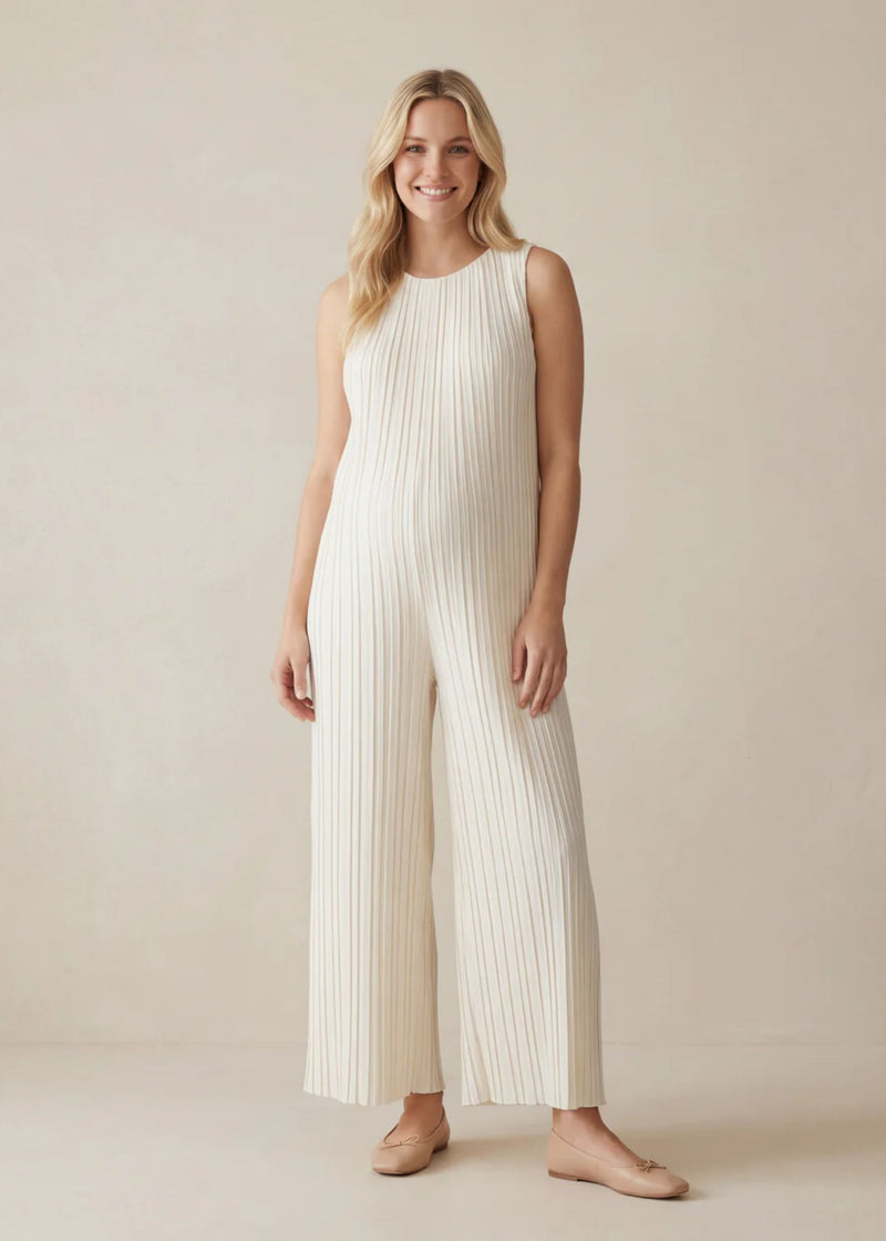 Smiling woman in a sleeveless white pleated Tencel jumpsuit with wide legs and a flowy fit.