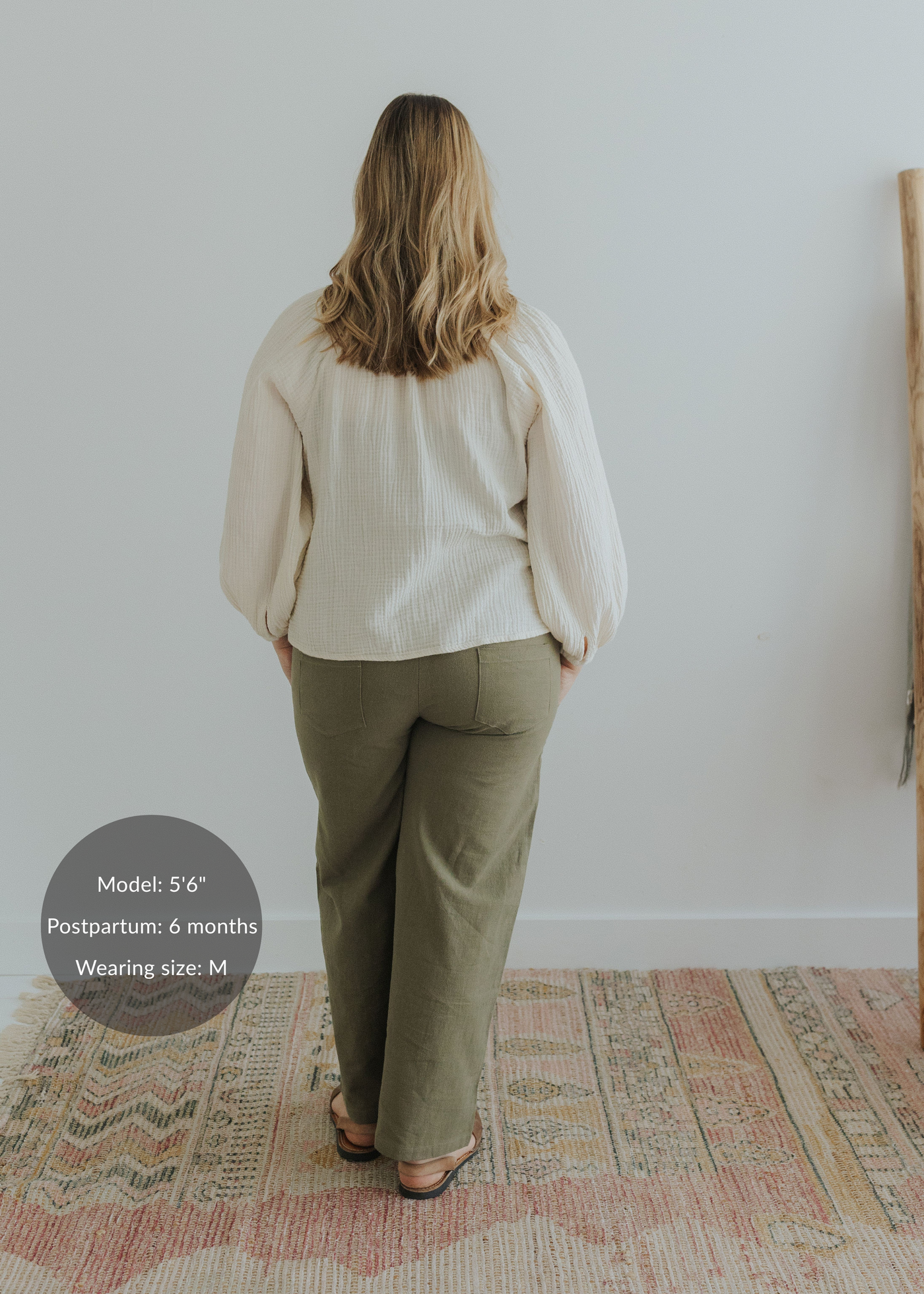 Back view of a woman wearing olive green wide-leg linen pants with a smocked waistband.
