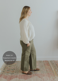 Woman in olive green wide-leg linen pants with smocked waist, paired with a cream blouse.