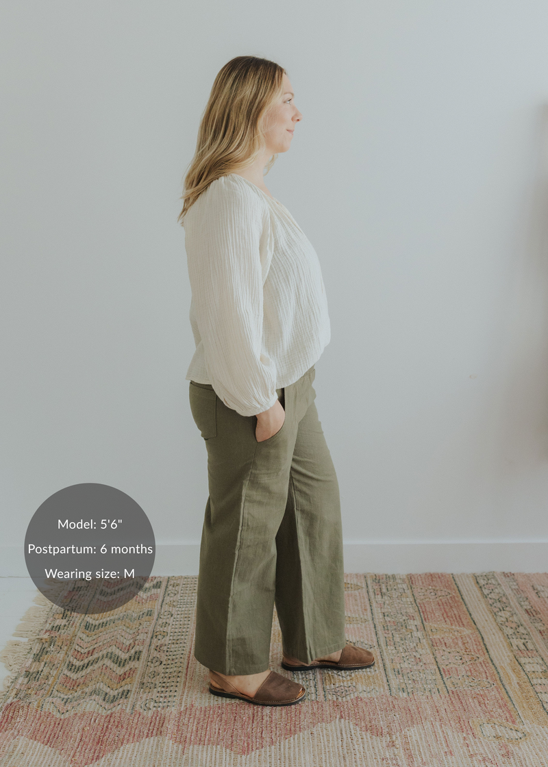 Woman in olive green wide-leg linen pants with smocked waist, paired with a cream blouse.