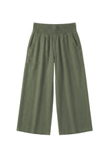 Olive green wide-leg linen pants with a smocked waistband and side pockets.