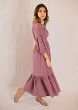 Woman in a mauve Eliza maternity maxi dress with smocked waist, balloon sleeves, and ruffle skirt.