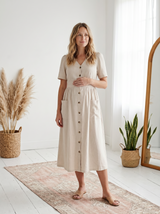 Pregnant woman in a beige linen-cotton button-front nursing dress with V-neck, short puffed sleeves, and patch pockets.