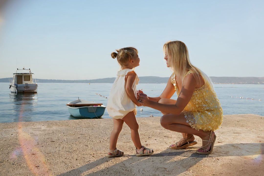 Jackie Volney crouching with her daughter by the water at golden hour