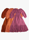 Three preloved Emme's tiered maxi dresses in rust, orange, and plum with smocked bodices and balloon sleeves.